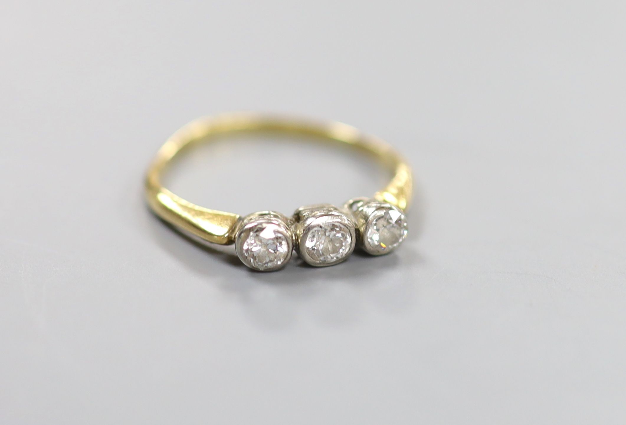 An 18ct and collet set three stone diamond ring, size R, gross weight 2.6 grams.